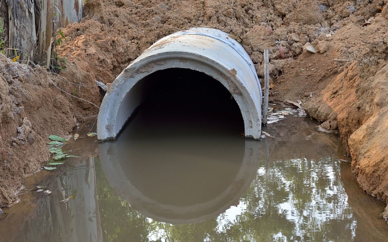 Culvert installation with corrugated pipe being placed in a trench to manage water flow under a driveway