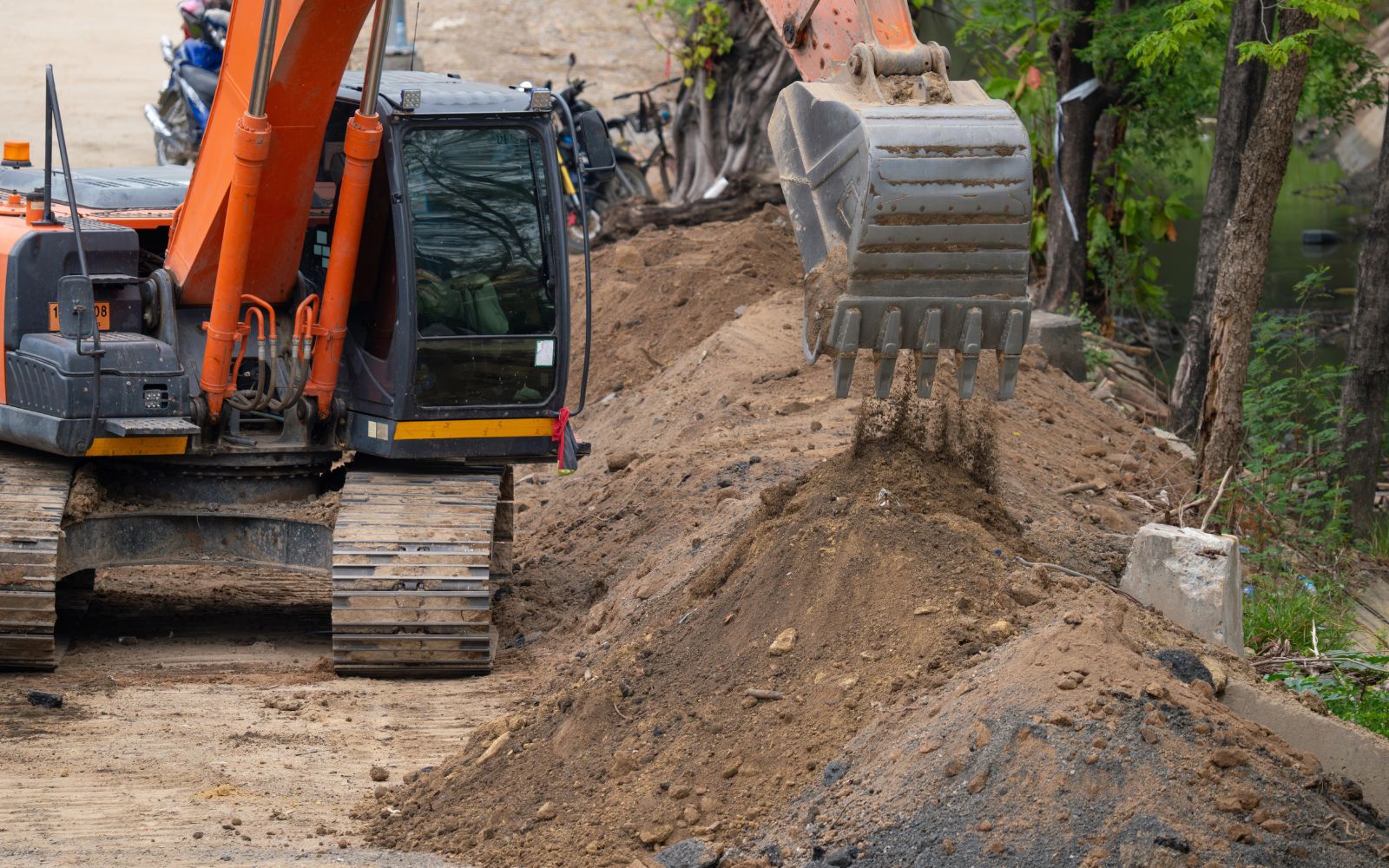 Excavator creating a level grade on uneven ground, preparing soil for future construction or landscaping