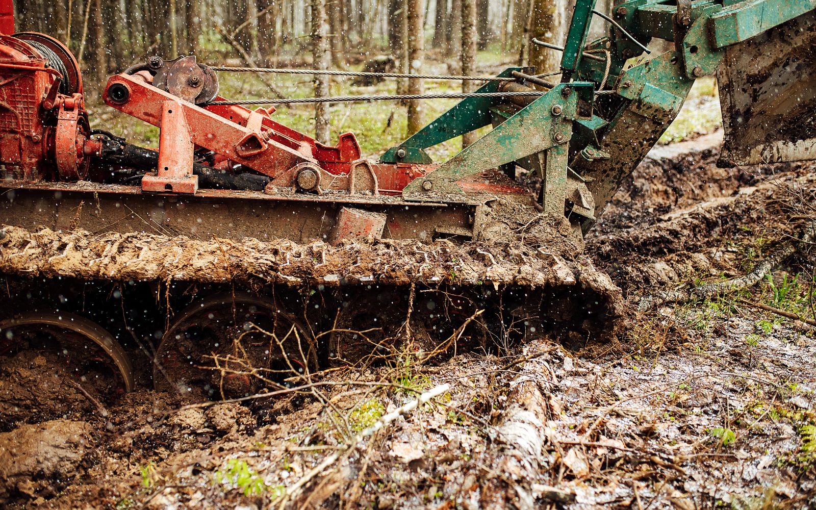 Forestry mulching machine clearing dense vegetation and brush on wooded land.
