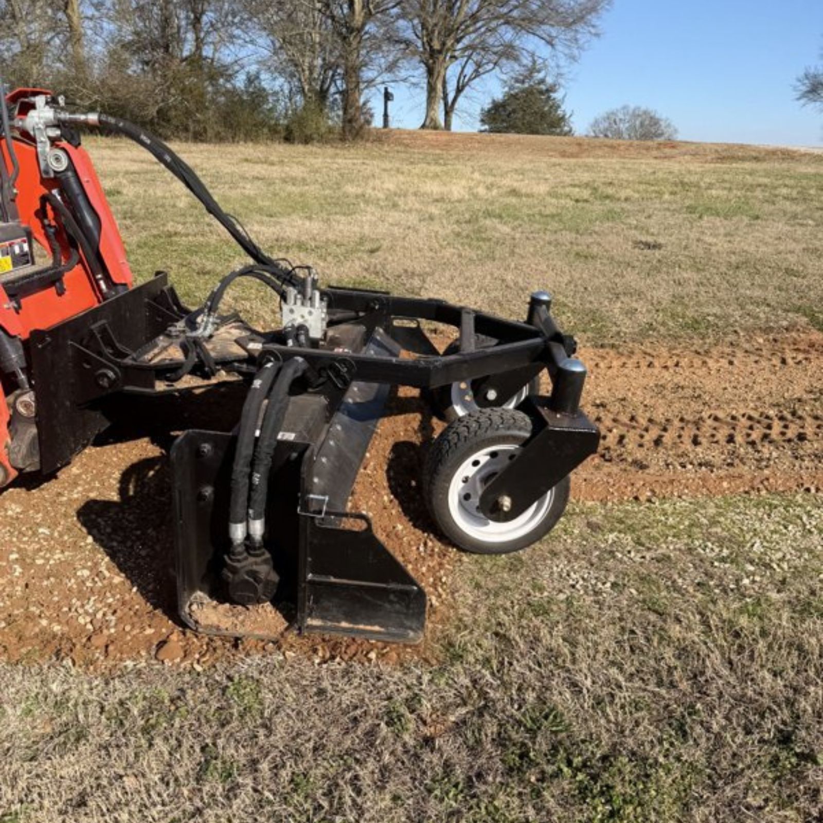 A heavy-duty power grader attachment leveling a gravel driveway for site preparation by Ground Truth Land Pros.