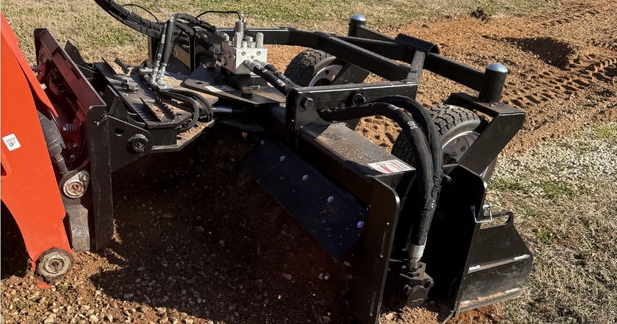 Close-up of a high-performance land plane attachment leveling and smoothing a gravel driveway surface