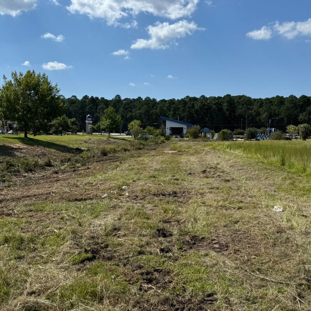 Open grassy field with freshly cut and uneven ground in the foreground