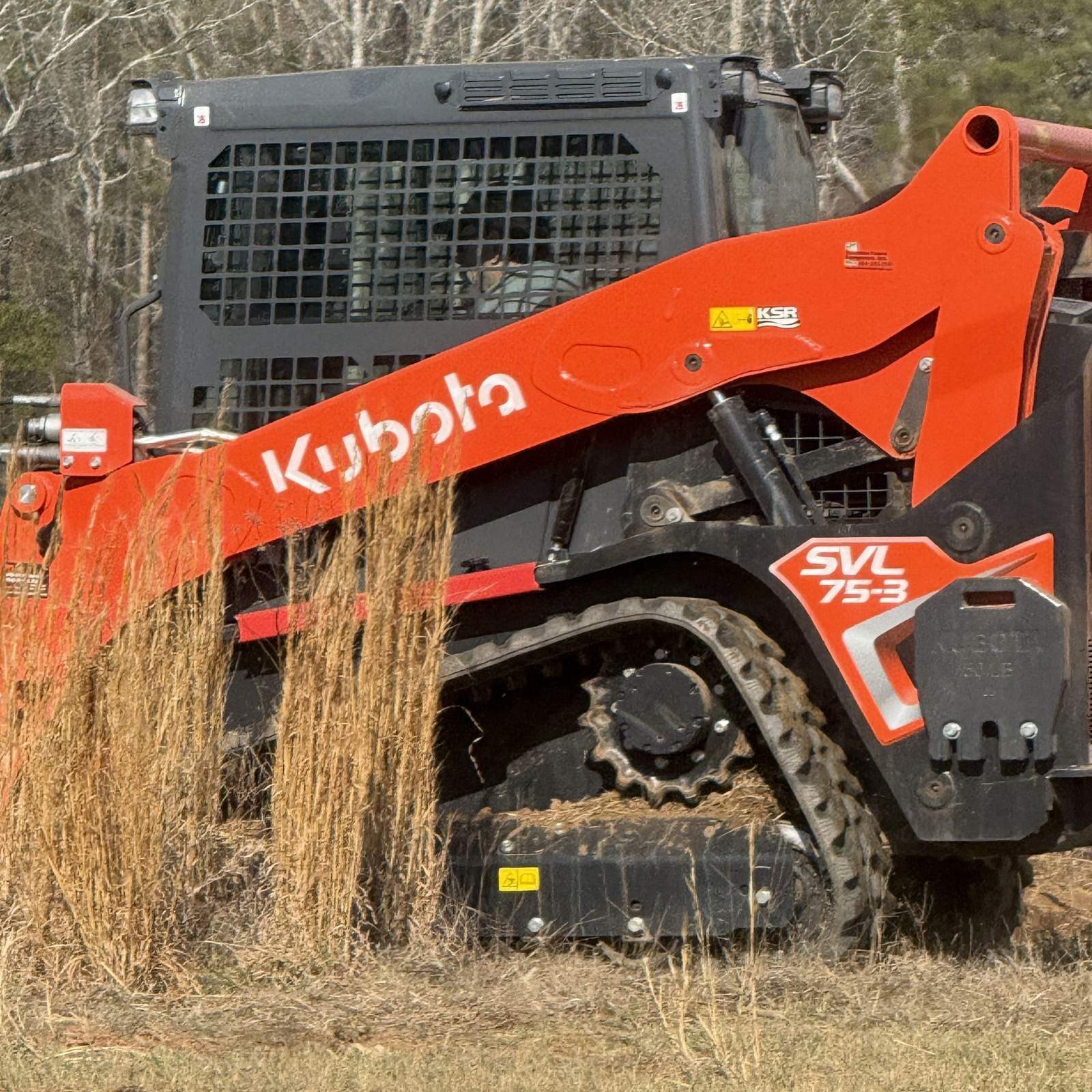 Side view of a Kubota SVL 75-3 compact track loader used for residential site preparation and driveway repair
