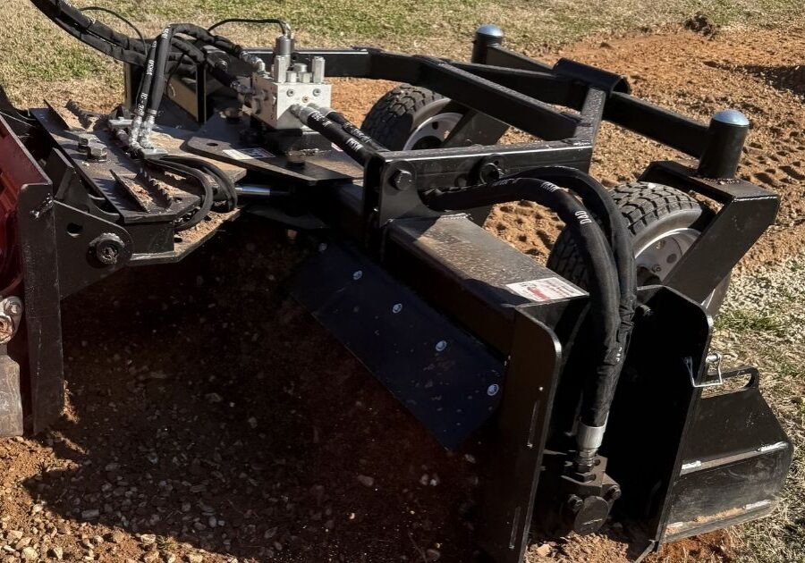 Close-up of a high-performance land plane attachment leveling and smoothing a gravel driveway surface